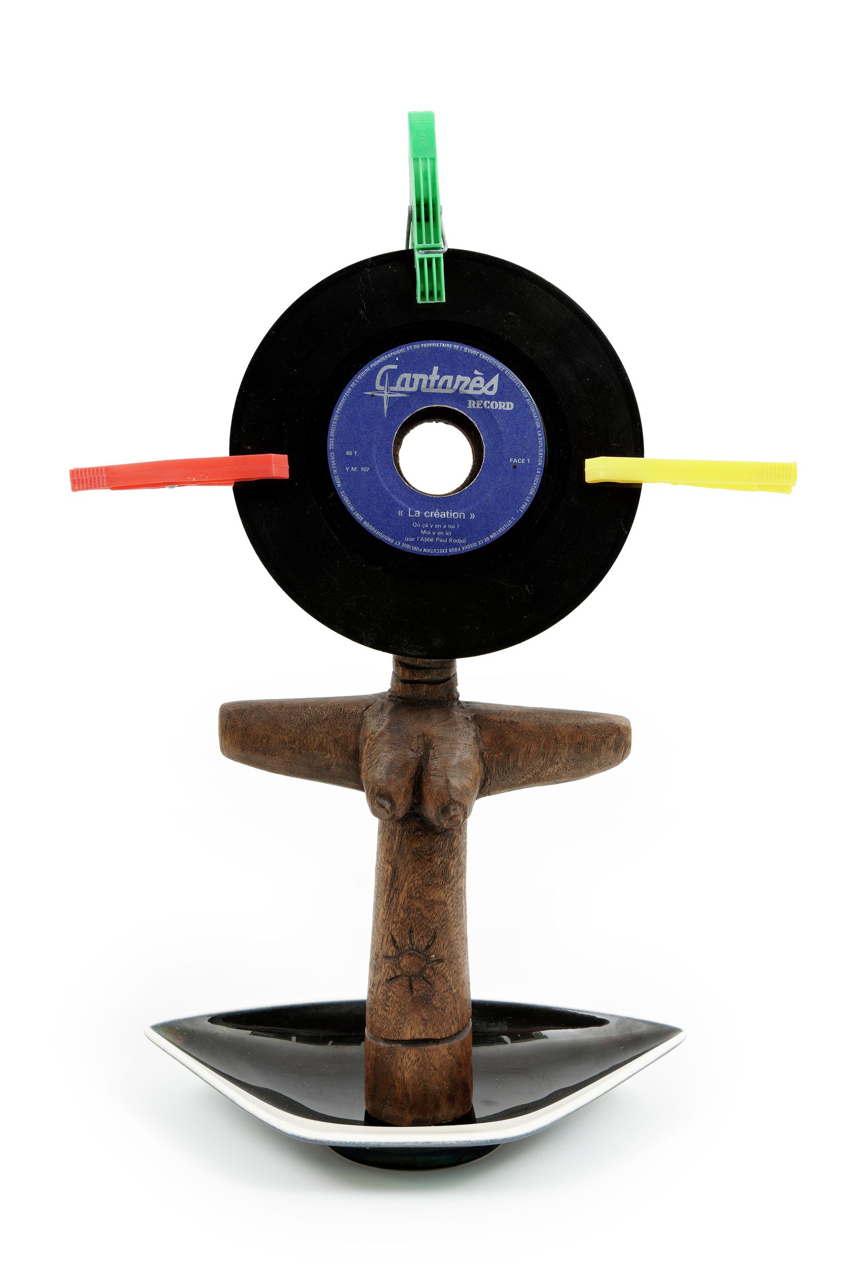 Présence Panchounette, Ashanti de faire votre connaissance, 1985 Statue en bois exotique, cendrier en faïence, disque vinyl 45tr (la création du père Kodjo) et pinces à linge44 × 30 × 10 cm / 17 3/8 × 11 6/8 × 3 7/8 in.